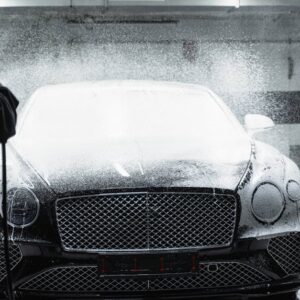 Black luxury car receiving a foamy wash in an indoor car wash service. - Photo by Tima Miroshnichenko on Pexels